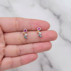 Pair of silver earrings with colorful gemstones held between fingers.