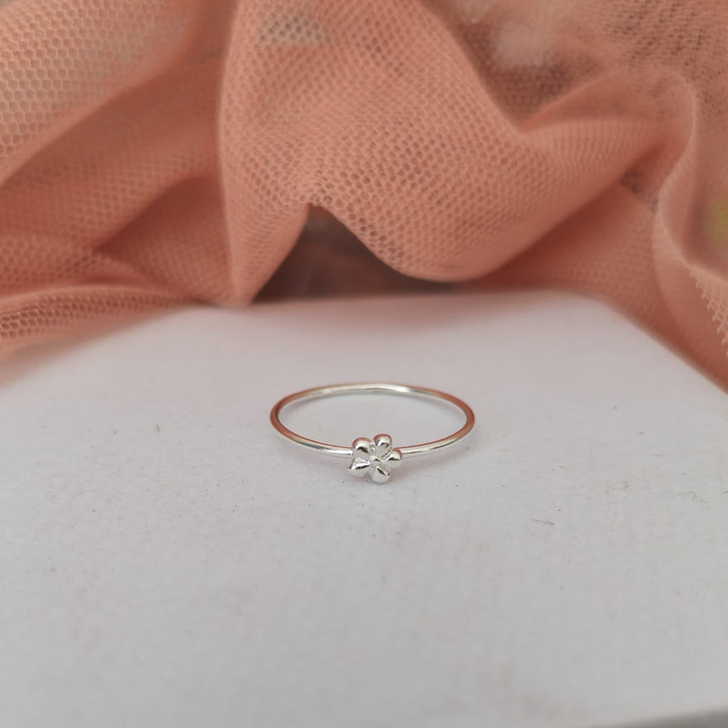 Silver ring with a flower design on a light pink fabric background