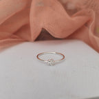 Silver ring with a flower design on a light pink fabric background