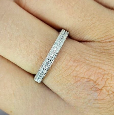 A sterling silver eternity band with cubic zirconia detail, worn on a person's hand.