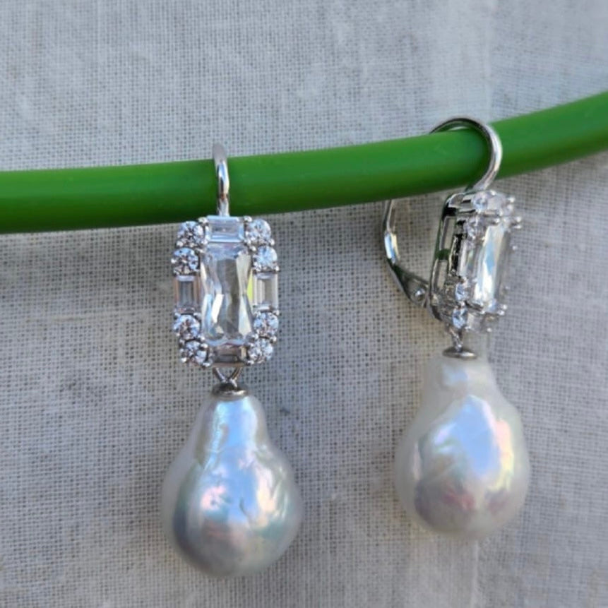 Pearl earrings with silver accents on a gray background