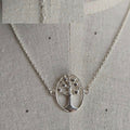 Silver necklace with a tree pendant on a textured gray background
