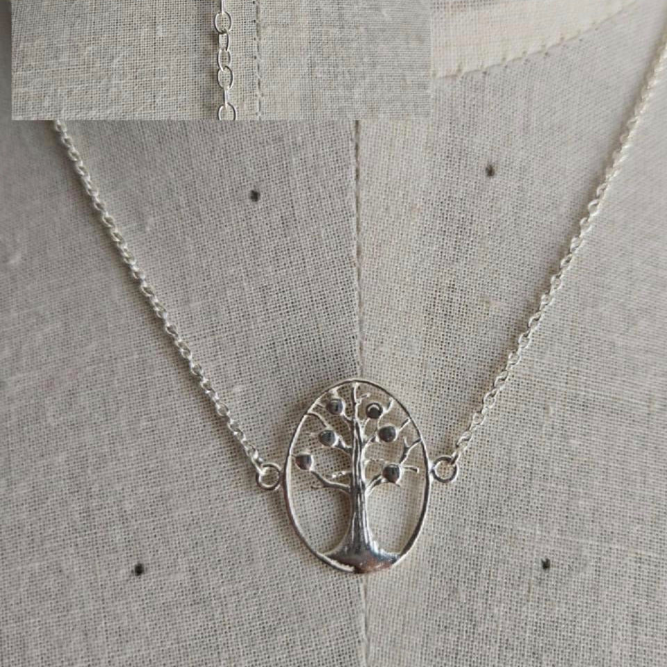 Silver necklace with a tree pendant on a textured gray background