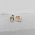 Gold stud earrings with clear gemstones on a light gray background