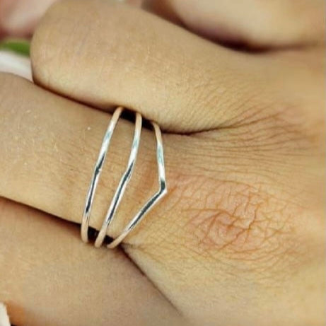 A sterling silver three band ring worn on a person's finger.