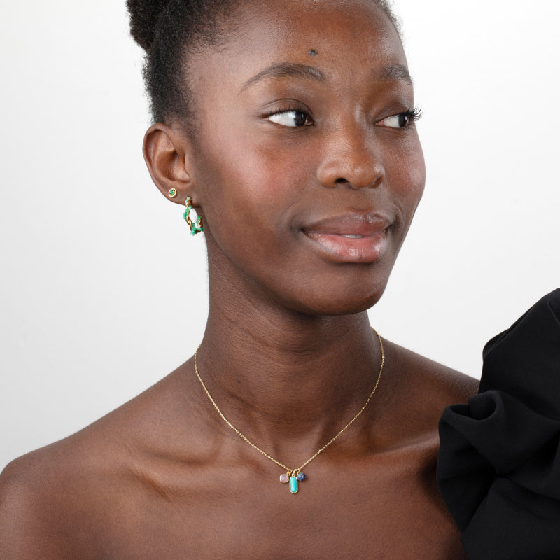 Woman wearing a gold necklace with a pendant on a plain background