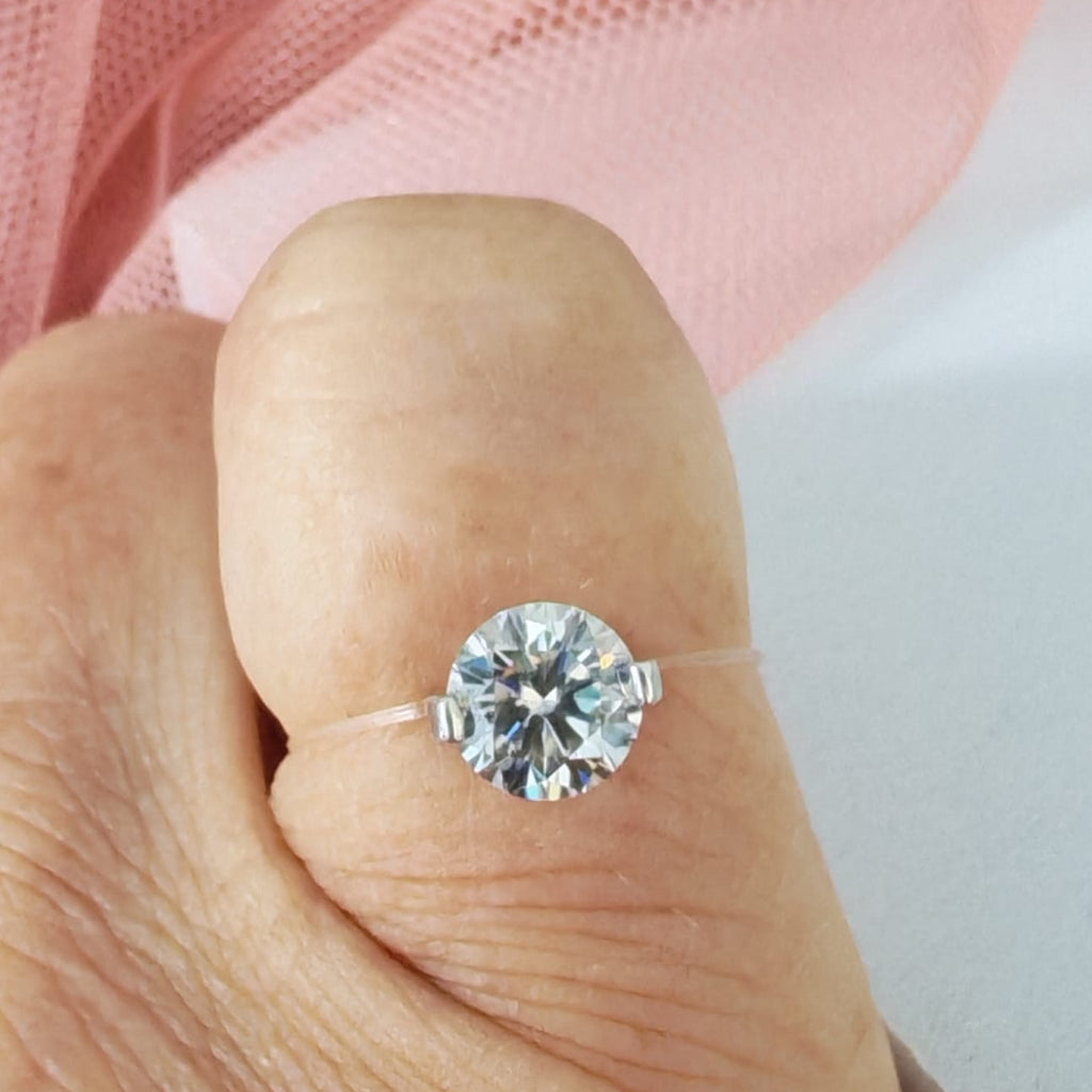 Diamond ring on a finger with a soft pink fabric background