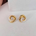 Gold spiral earrings on a light gray surface
