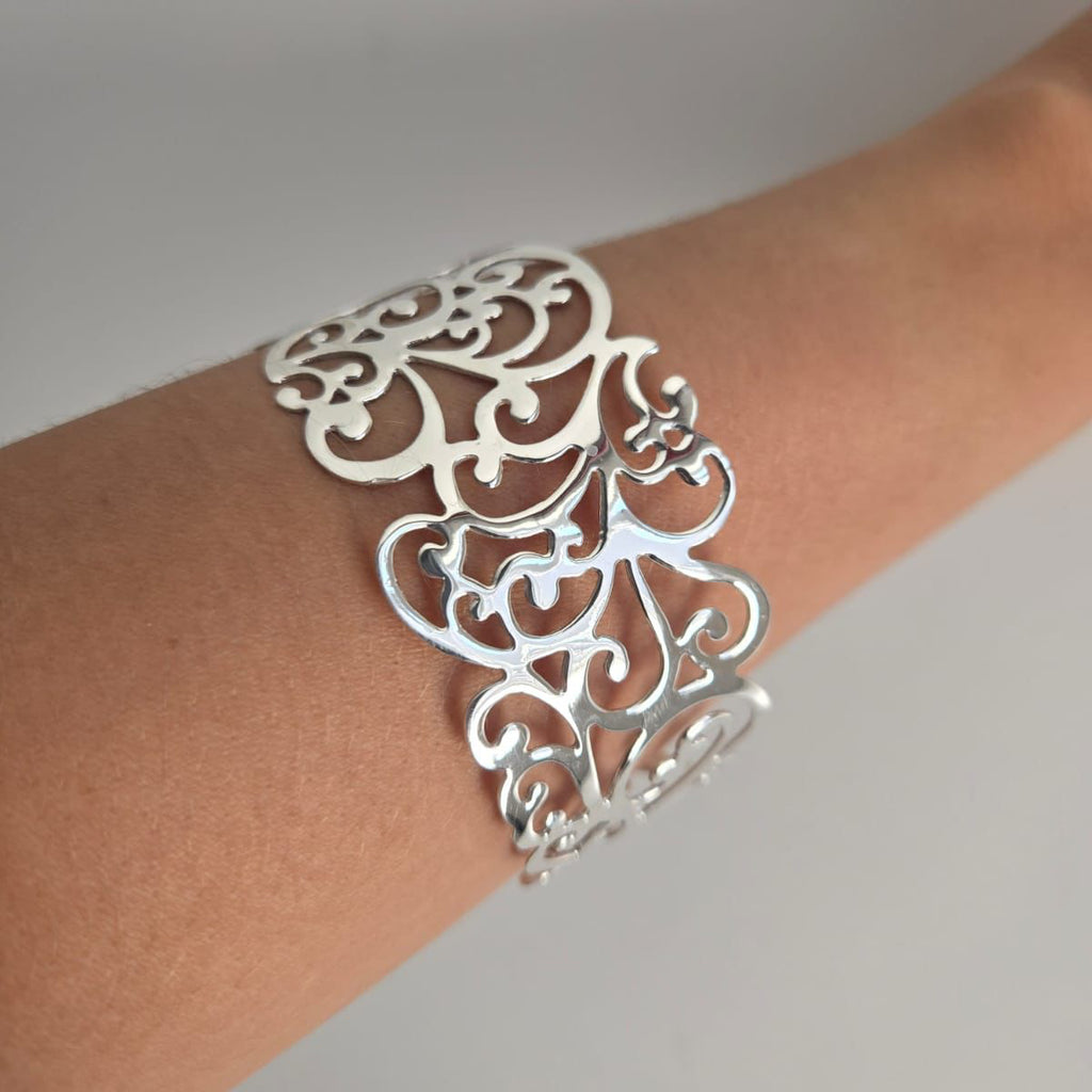 Silver filigree bracelet on a wrist against a neutral background