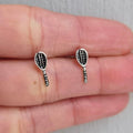 Silver tennis racket earrings on a hand