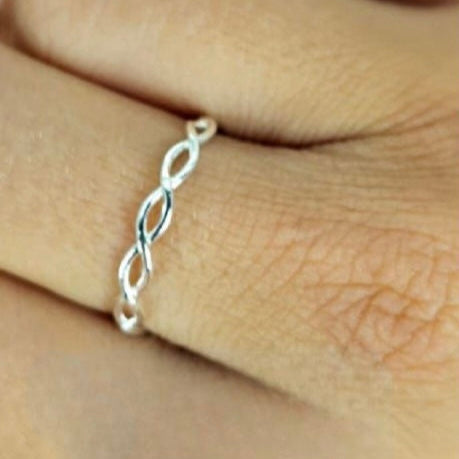 A sterling silver 'koeksister' band ring worn on a person's finger, displaying a braided design.