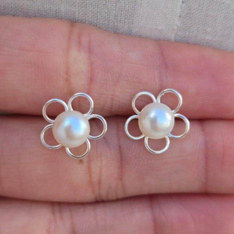Flower-shaped pearl earrings on a hand
