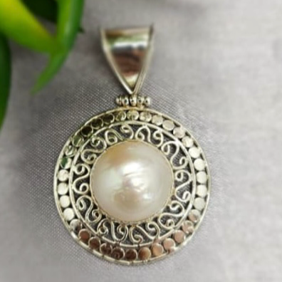 A sterling silver pendant featuring a white Mabe pearl, displayed against a neutral background.
