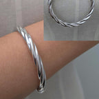 Silver braided bracelet on a wrist with a close-up inset.