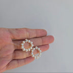 A pair of 18mm Freshwater pearl hoop earrings on a stud, held between fingers against a neutral background.