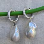 Pearl earrings with silver hoop designs on a gray background