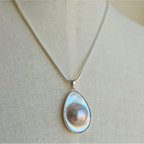 A Blister Mabe Pearl pendant set in sterling silver, displayed on a mannequin.