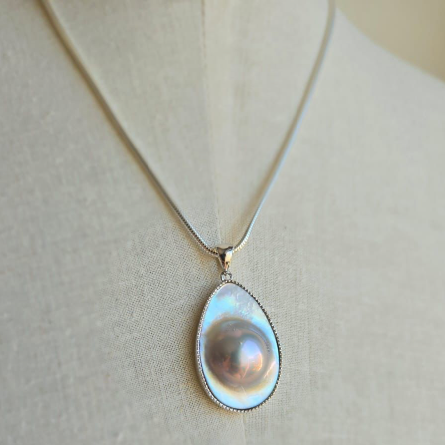A Blister Mabe Pearl pendant set in sterling silver, displayed on a mannequin.