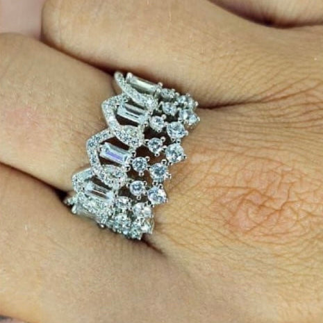 A close-up of a person's hand showcasing a sterling silver ring with a intricate cubic zirconia design.
