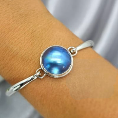 A sterling silver bracelet featuring a central mabe pearl, displayed on a person's wrist.