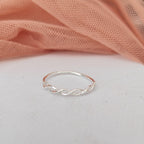 Silver twisted ring on a light pink fabric background