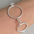 Silver hoop earring on a person's ear with a plain background