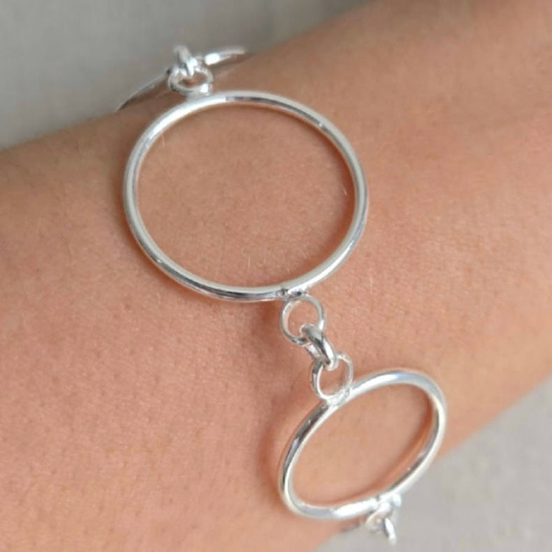 Silver hoop earring on a person's ear with a plain background