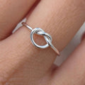 Silver ring with a unique design on a finger against a neutral background