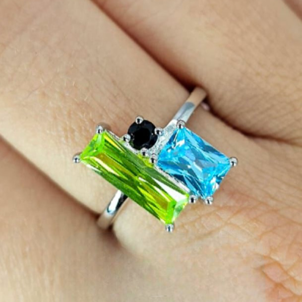 A sterling silver ring with rectangular cubic zirconia stones set in a vise on a person's hand.