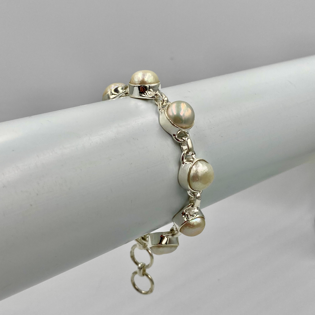 A sterling silver bracelet with a series of pearl beads, displayed against a white background.