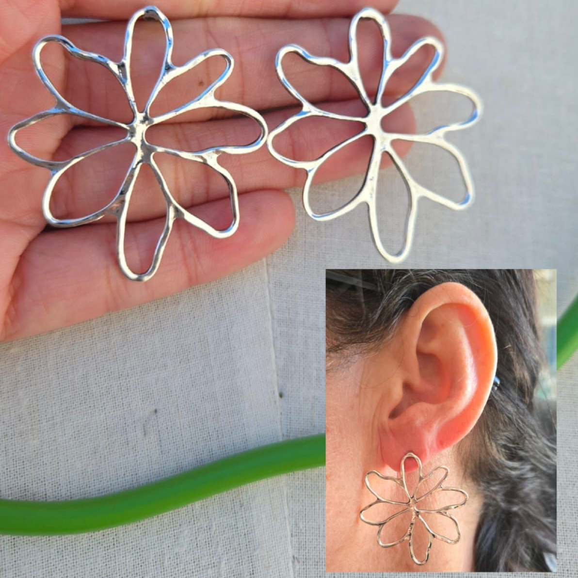 Silver flower-shaped earrings held in a hand with an inset showing them worn on an ear.