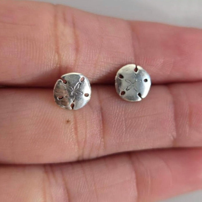 Silver sand dollar earrings on a hand