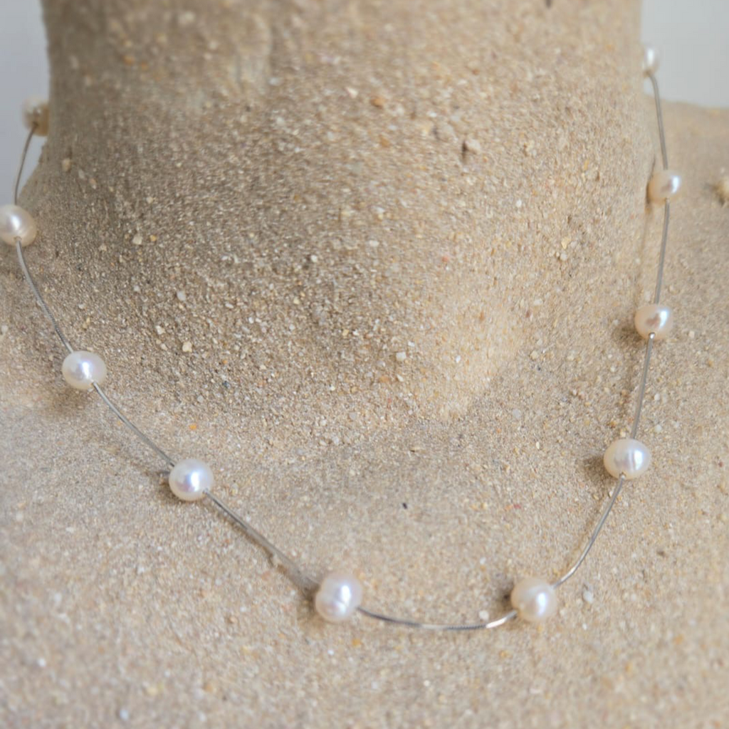 Pearl necklace on a mannequin bust with a neutral background