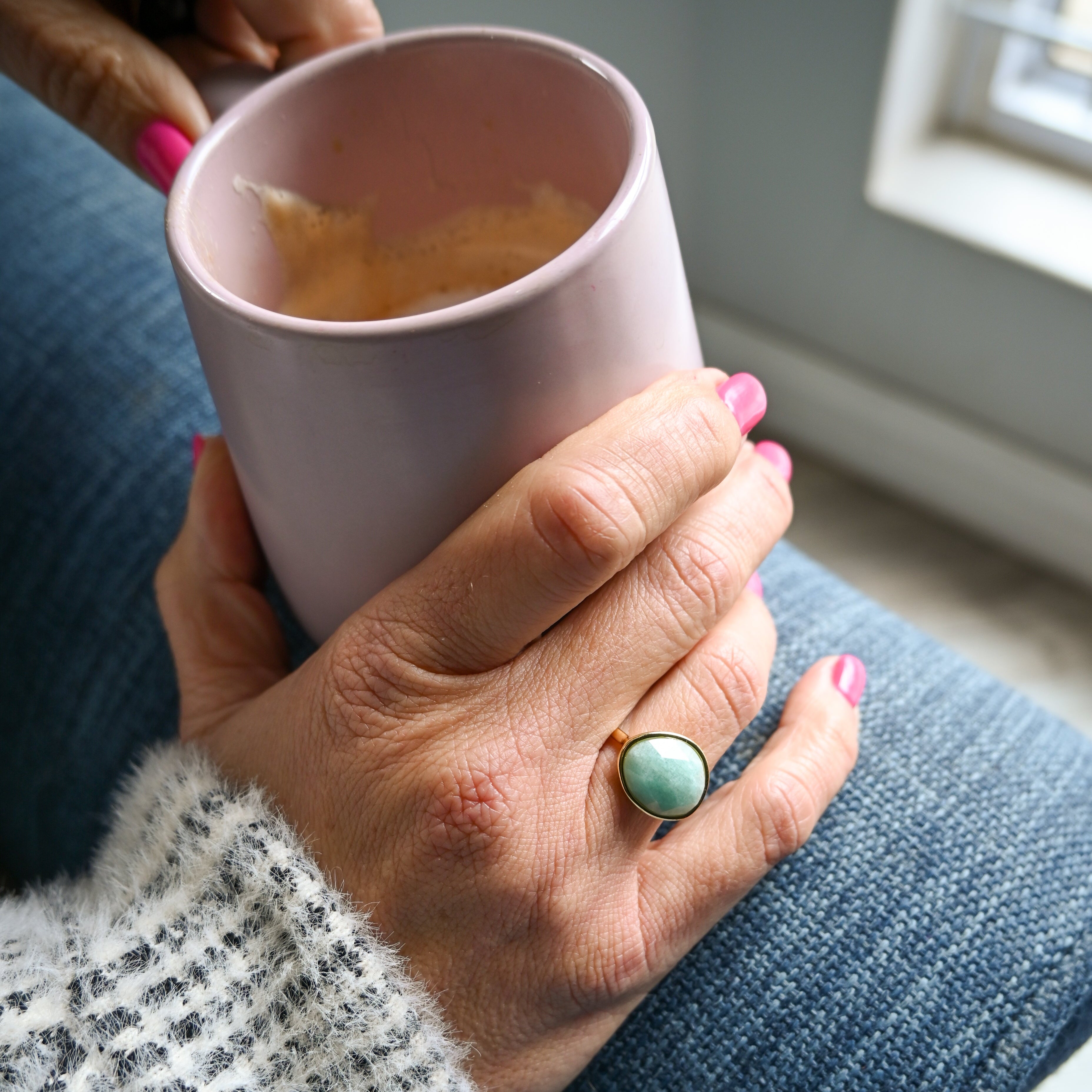 Hand holding a pink mug with a blurred background