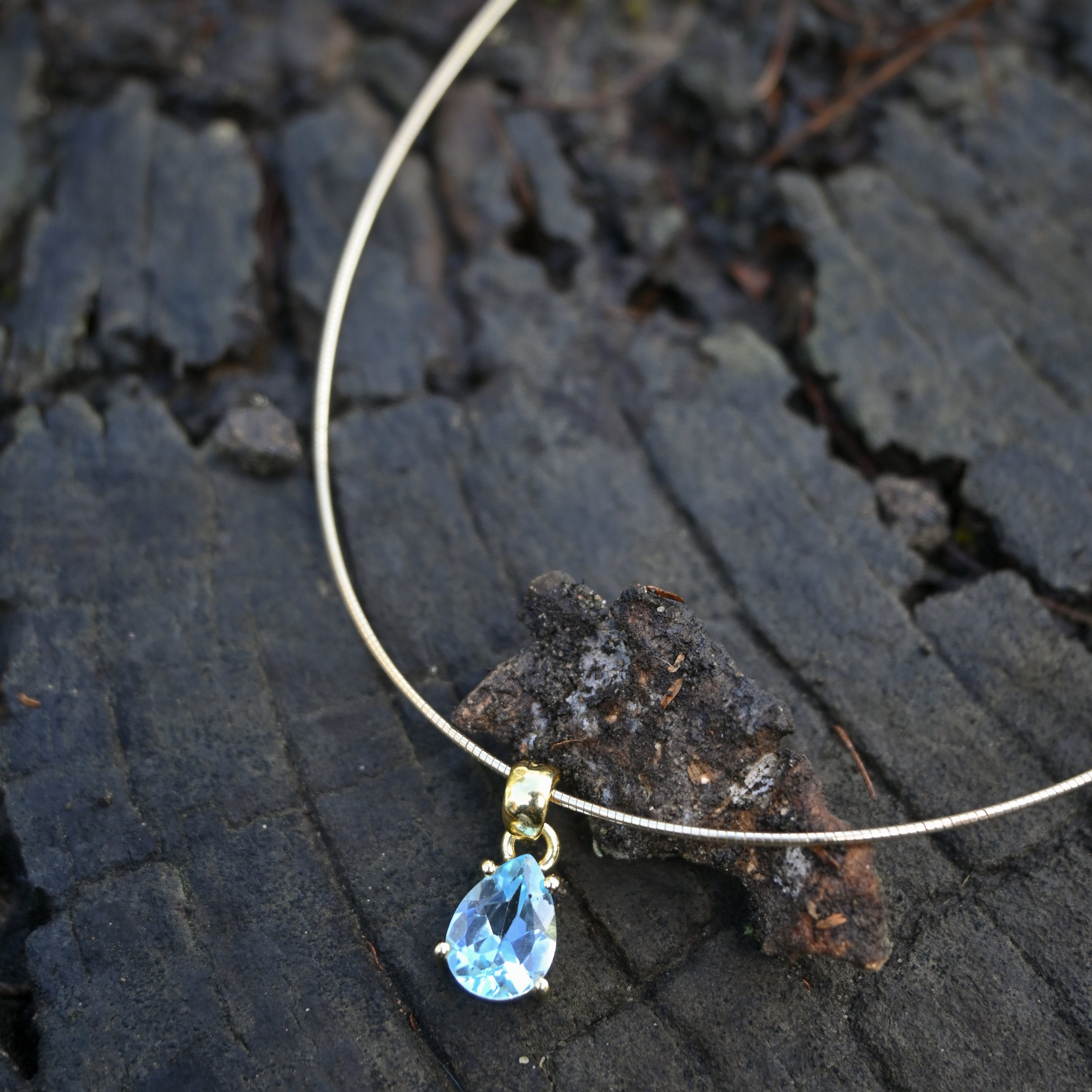 Necklace with a blue teardrop pendant on a textured dark surface