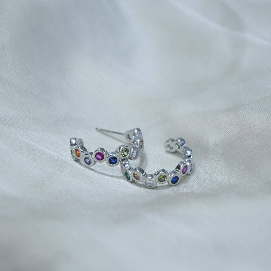 Silver earring with colorful gemstones on a white fabric background