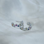 Silver earring with colorful gemstones on a white fabric background