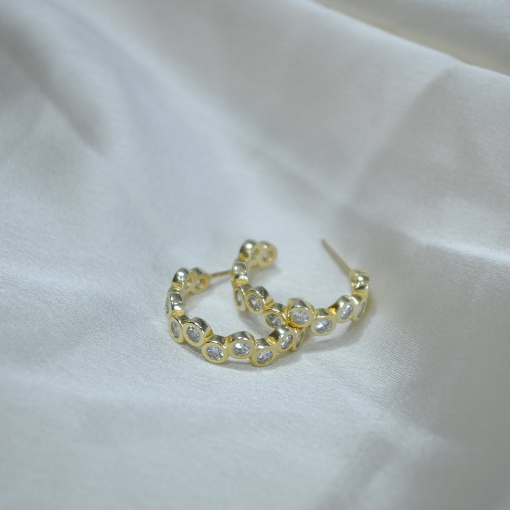 Gold hoop earrings on a white fabric background