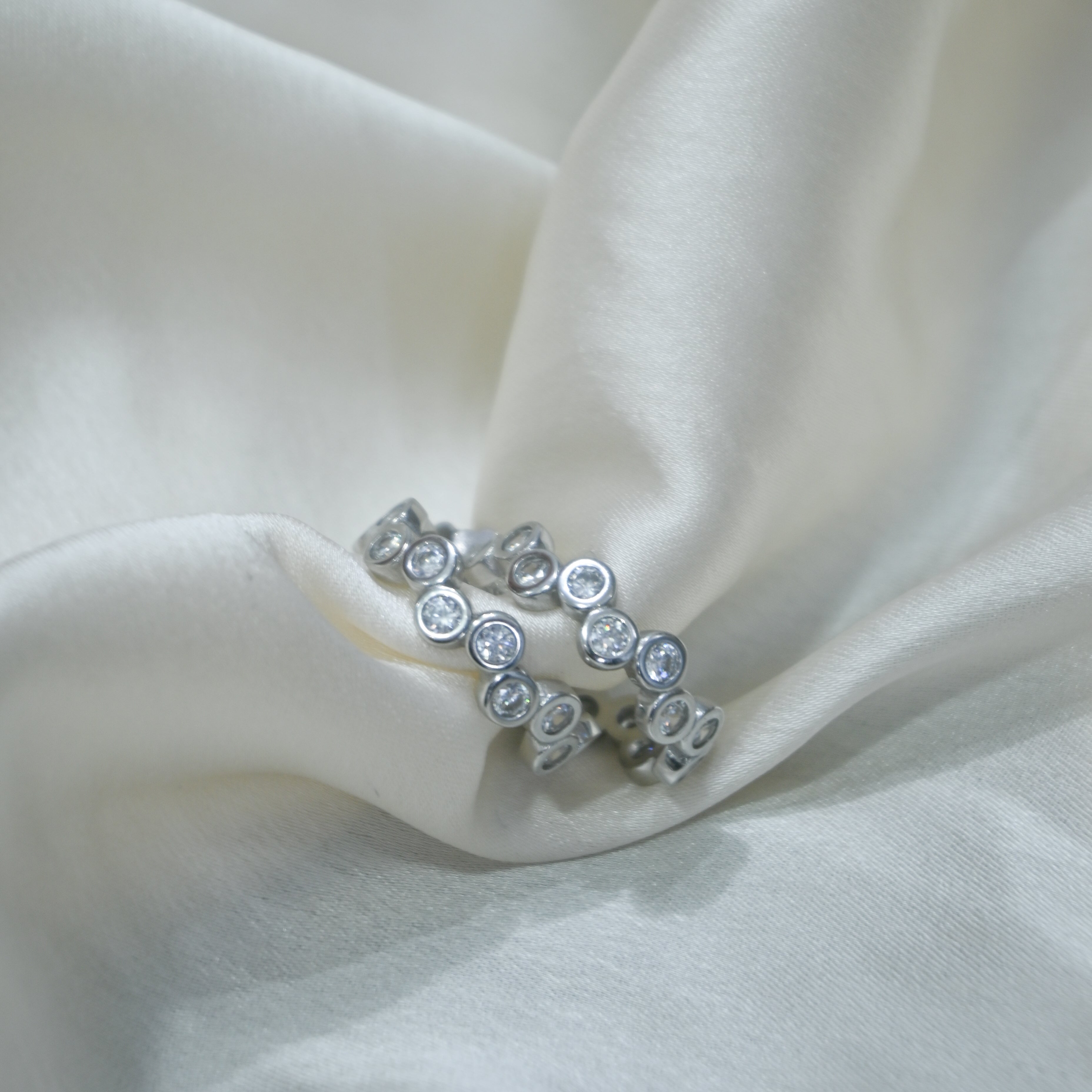 Silver ring with embedded stones on a white fabric background
