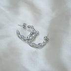 Silver hoop earrings on a white fabric background