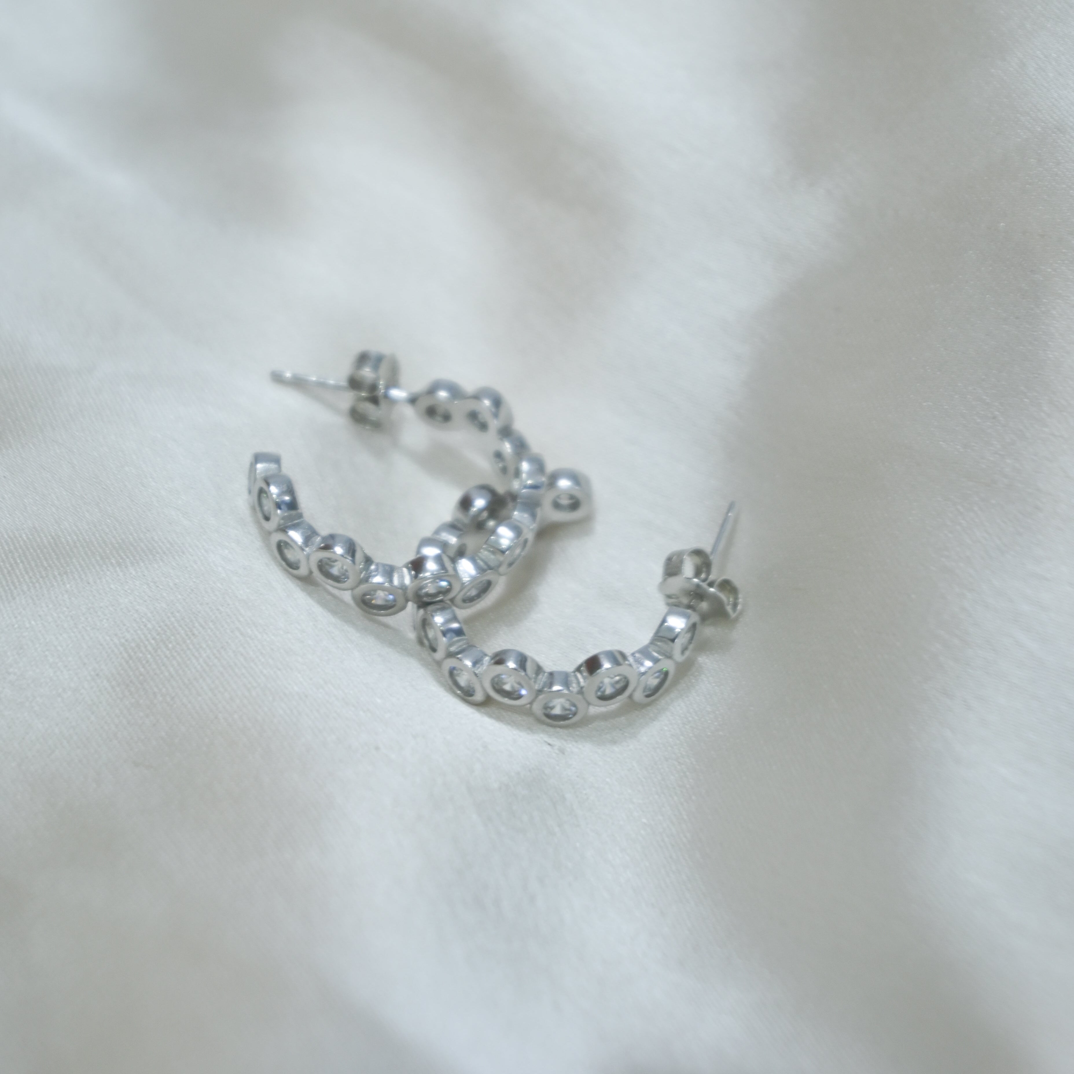 Silver hoop earrings on a white fabric background