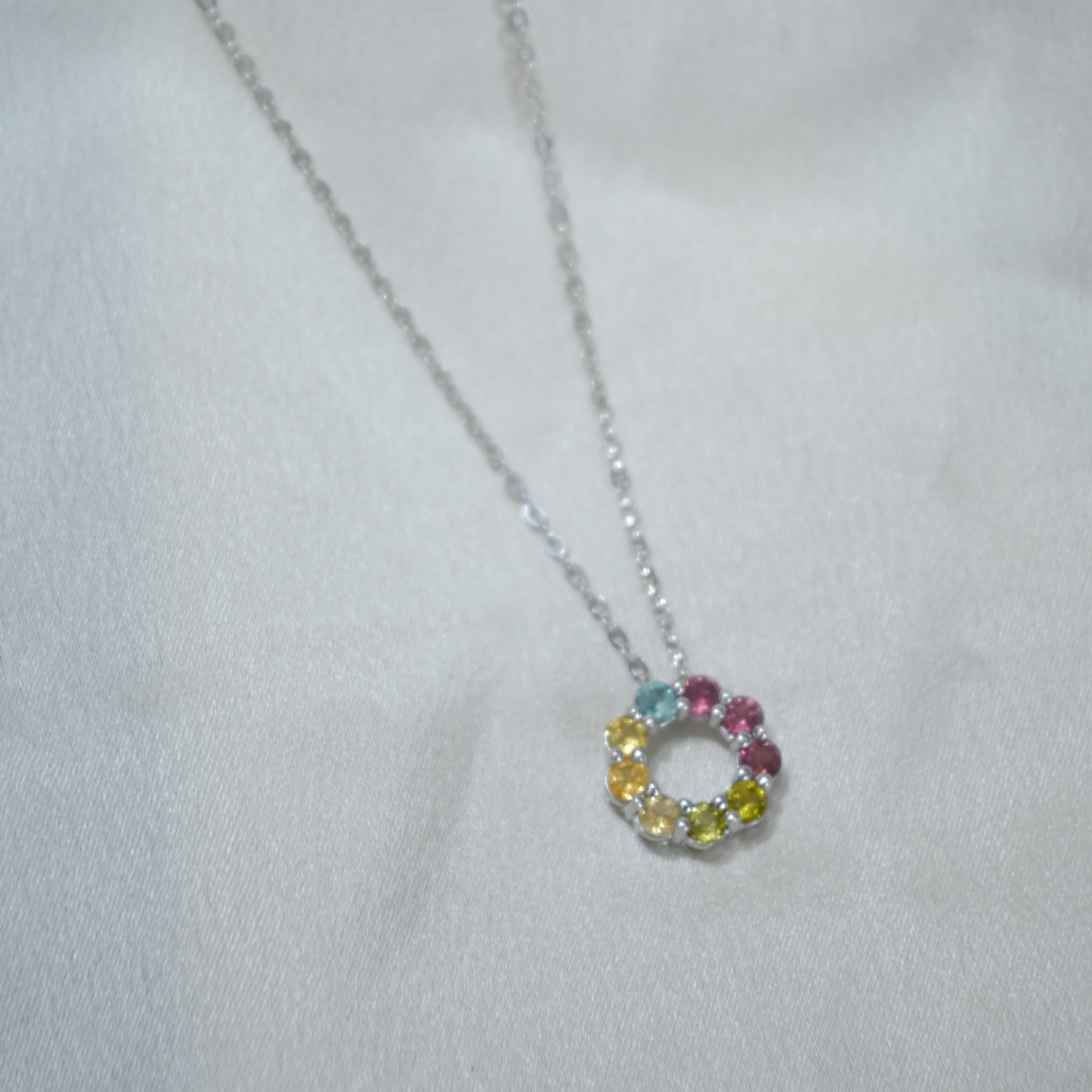 Necklace with a circular pendant featuring multicolored stones on a light gray background