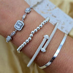 Silver bracelets on a wrist with a blurred background