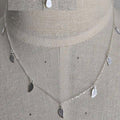 Silver necklace with leaf-shaped pendants on a mannequin bust.