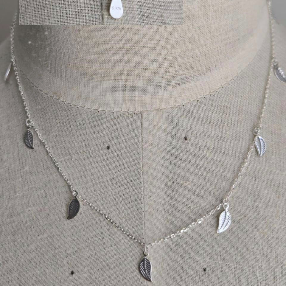 Silver necklace with leaf-shaped pendants on a mannequin bust.