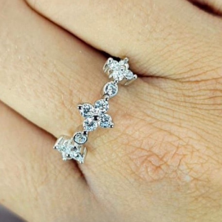 A sterling silver ring with intricate flower detailing and a sparkling cubic zirconia stone, displayed on a person's hand.