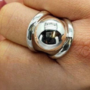 A sterling silver ball ring on a person's finger, with a polished surface and a reflective silver color.
