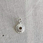 Silver pendant on a textured gray fabric background
