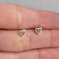 Silver heart-shaped earrings on a hand