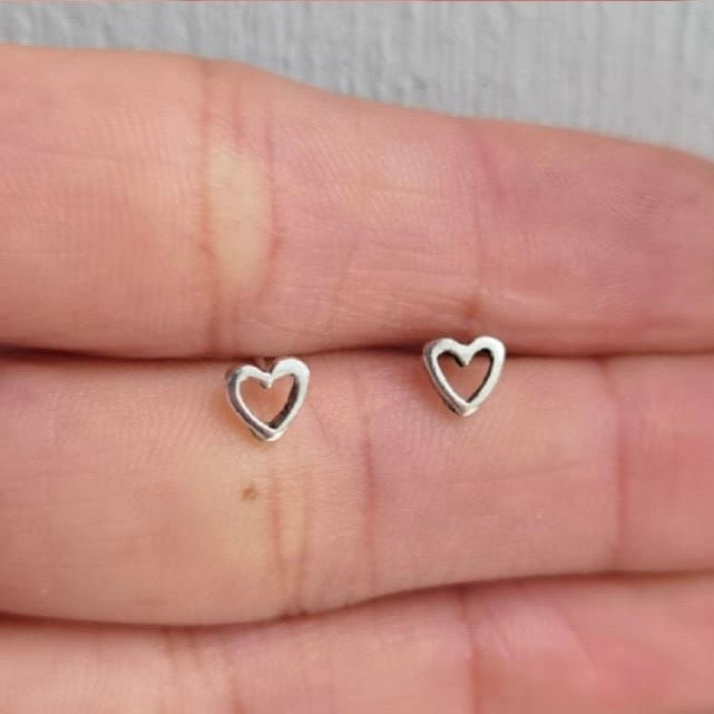 Silver heart-shaped earrings on a hand